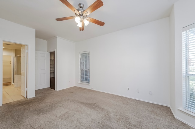 unfurnished bedroom featuring ensuite bath, light colored carpet, and ceiling fan