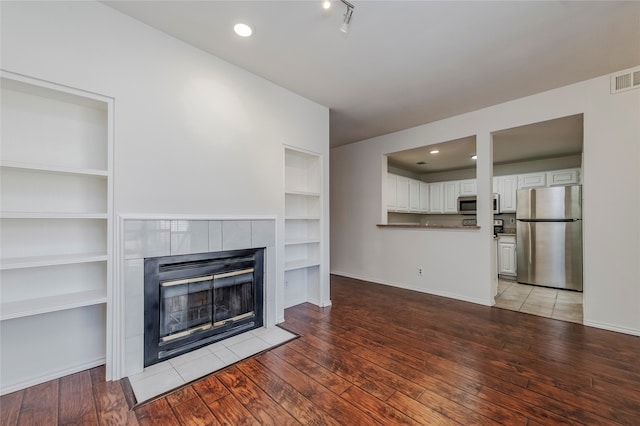 unfurnished living room with built in shelves, light hardwood / wood-style flooring, and a fireplace