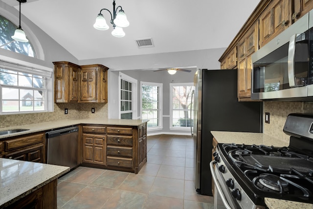 kitchen with appliances with stainless steel finishes, pendant lighting, plenty of natural light, and backsplash