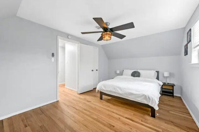 bedroom with light hardwood / wood-style flooring, vaulted ceiling, and ceiling fan