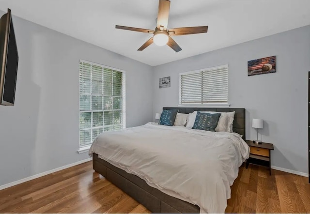 bedroom featuring multiple windows, wood-type flooring, and ceiling fan