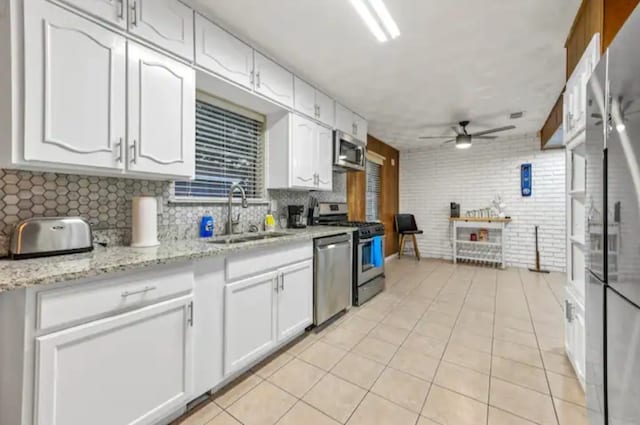 kitchen featuring sink, light tile patterned flooring, ceiling fan, stainless steel appliances, and white cabinets