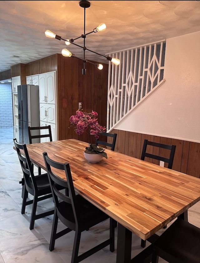 dining space featuring a notable chandelier and wood walls