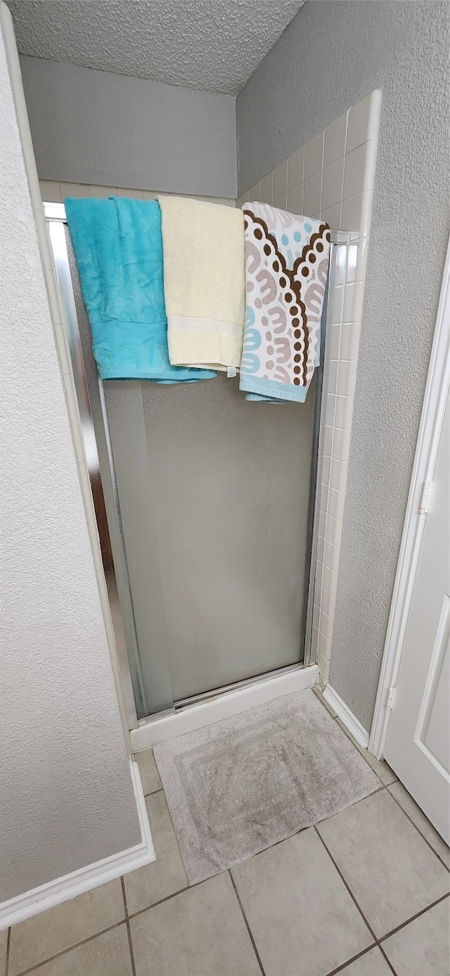 bathroom featuring a shower with door, a textured ceiling, and tile patterned flooring