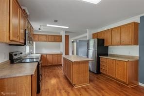 kitchen featuring appliances with stainless steel finishes, light wood-type flooring, and a kitchen island