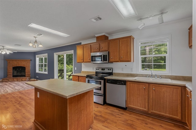 kitchen with a center island, decorative light fixtures, light wood-type flooring, appliances with stainless steel finishes, and ceiling fan with notable chandelier