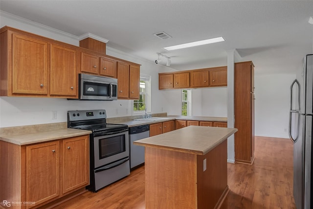 kitchen with light hardwood / wood-style floors, a center island, stainless steel appliances, and crown molding