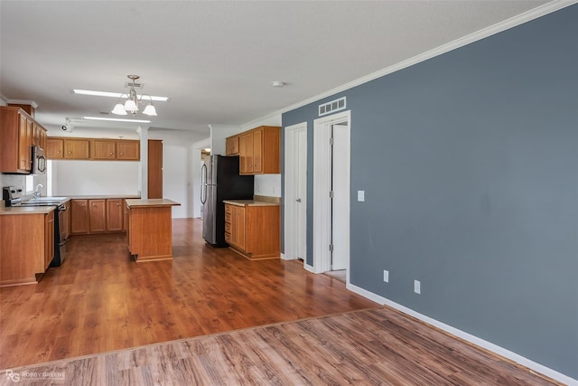 kitchen with appliances with stainless steel finishes, crown molding, dark hardwood / wood-style floors, and a center island