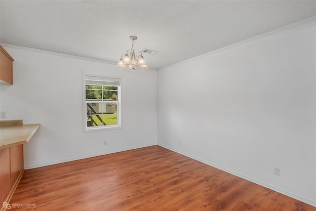 unfurnished dining area with crown molding, a textured ceiling, a chandelier, and wood-type flooring