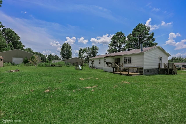 view of yard featuring a deck, an outbuilding, and a garage