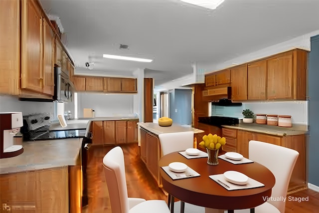 kitchen featuring stove, hardwood / wood-style floors, a center island, and ventilation hood