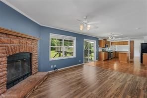 unfurnished living room featuring ceiling fan, wood-type flooring, ornamental molding, and a fireplace