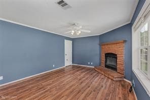 unfurnished living room with crown molding, a brick fireplace, dark hardwood / wood-style floors, and ceiling fan