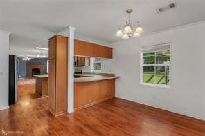 kitchen with kitchen peninsula, an inviting chandelier, and dark hardwood / wood-style flooring