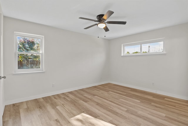 spare room featuring ceiling fan, a healthy amount of sunlight, and light wood-type flooring