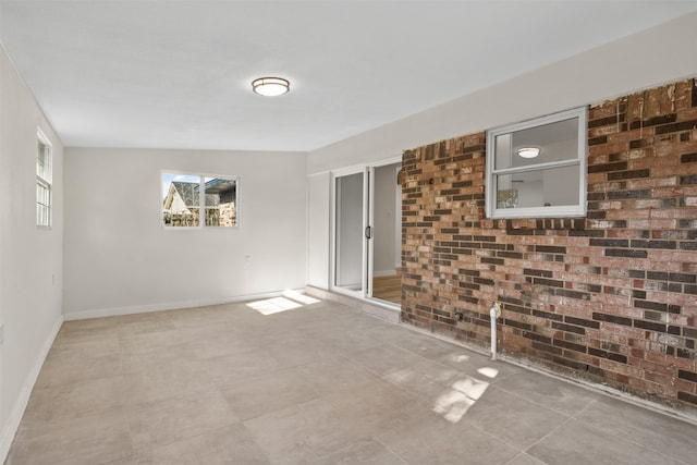 unfurnished room with brick wall and vaulted ceiling