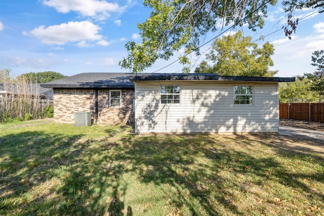 back of property with central AC unit and a lawn