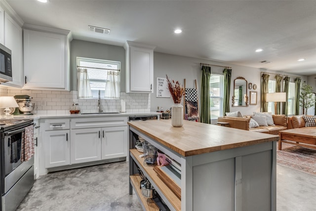 kitchen featuring white cabinetry, butcher block countertops, stainless steel appliances, and a center island