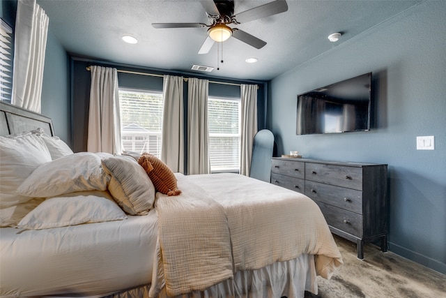 bedroom featuring ceiling fan, light carpet, and a textured ceiling