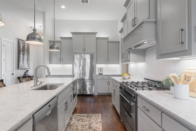 kitchen with pendant lighting, high quality appliances, sink, dark hardwood / wood-style floors, and custom range hood