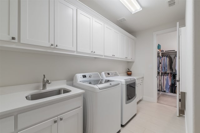 laundry room with washer and clothes dryer, cabinets, and sink