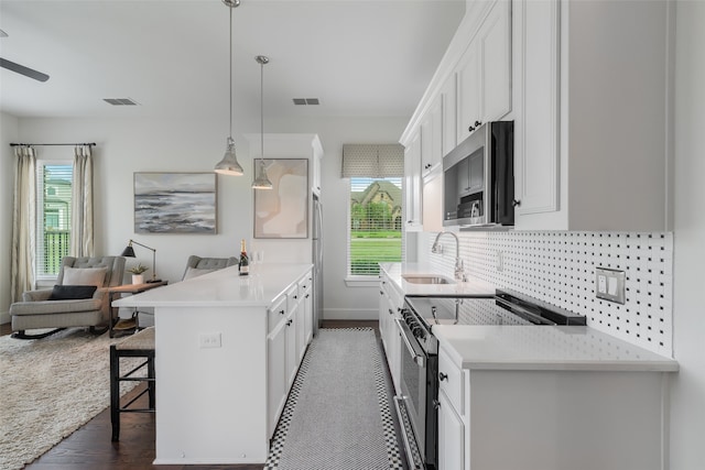 kitchen featuring white cabinets, sink, hanging light fixtures, dark hardwood / wood-style floors, and stainless steel appliances