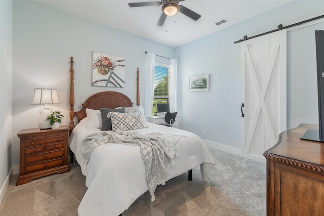 carpeted bedroom featuring a barn door and ceiling fan