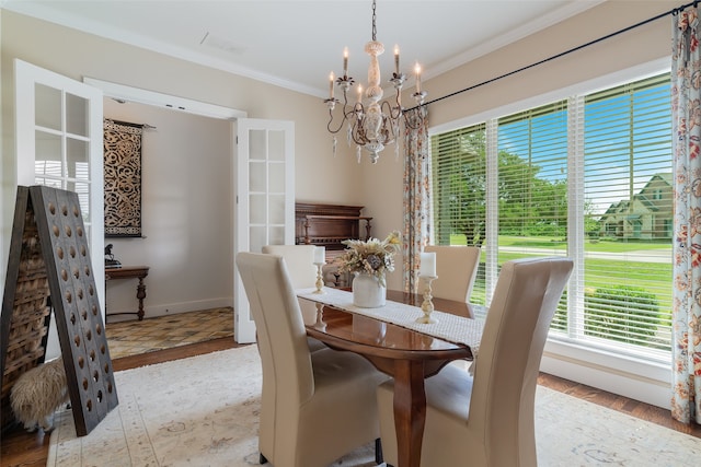 dining area with light hardwood / wood-style floors, ornamental molding, and a chandelier