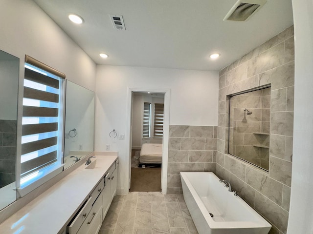 bathroom featuring vanity, independent shower and bath, and tile walls