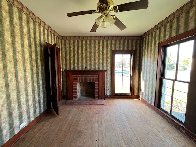 unfurnished living room featuring ceiling fan, a brick fireplace, plenty of natural light, and hardwood / wood-style floors