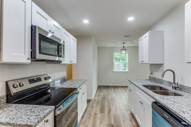 kitchen featuring sink, light stone counters, white cabinets, and appliances with stainless steel finishes