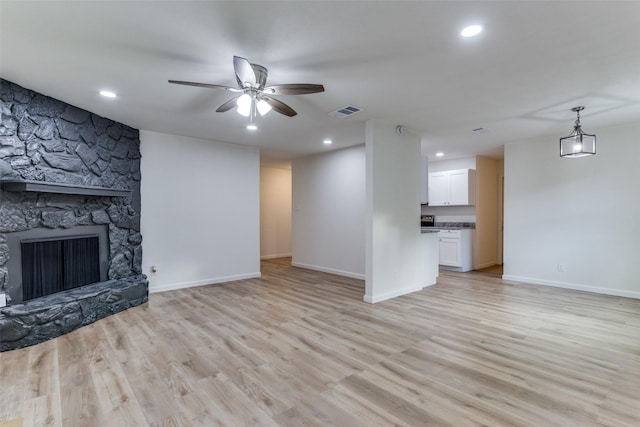 living room with a fireplace, light wood-type flooring, and ceiling fan