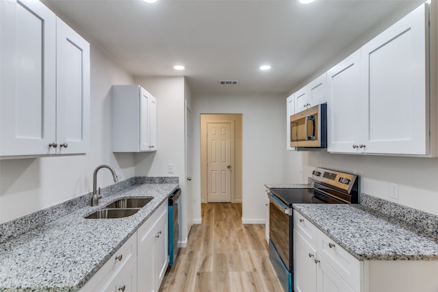 kitchen with sink, white cabinetry, light stone counters, and appliances with stainless steel finishes