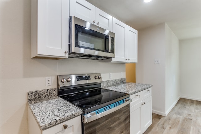 kitchen featuring light stone countertops, white cabinetry, stainless steel appliances, and light wood-type flooring