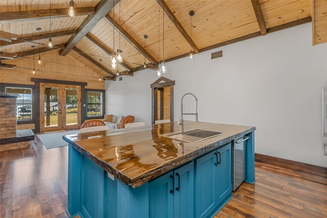 kitchen with pendant lighting, blue cabinets, sink, a center island with sink, and french doors