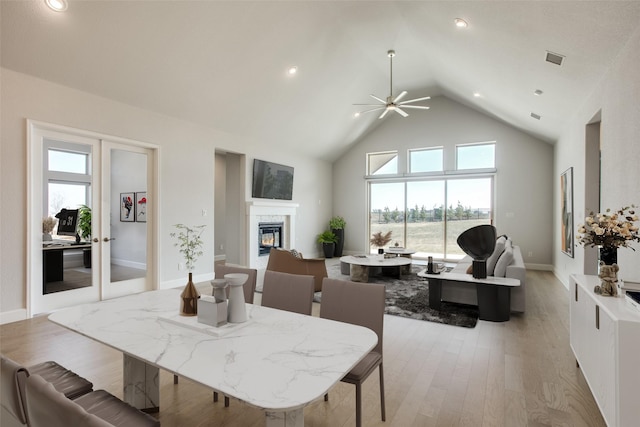 dining room with ceiling fan, light hardwood / wood-style flooring, and a high ceiling