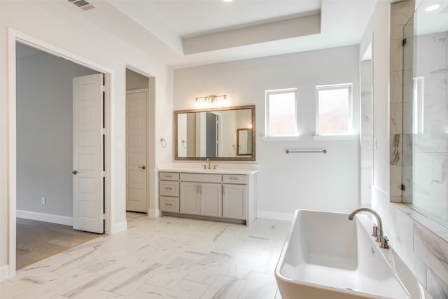 bathroom with a washtub, a raised ceiling, and vanity