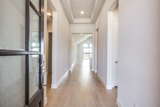 corridor featuring light hardwood / wood-style floors and a tray ceiling