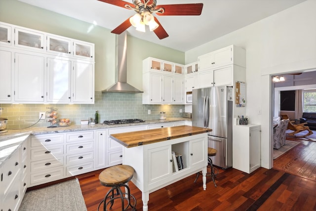 kitchen with decorative backsplash, wall chimney exhaust hood, dark wood-type flooring, white cabinetry, and appliances with stainless steel finishes