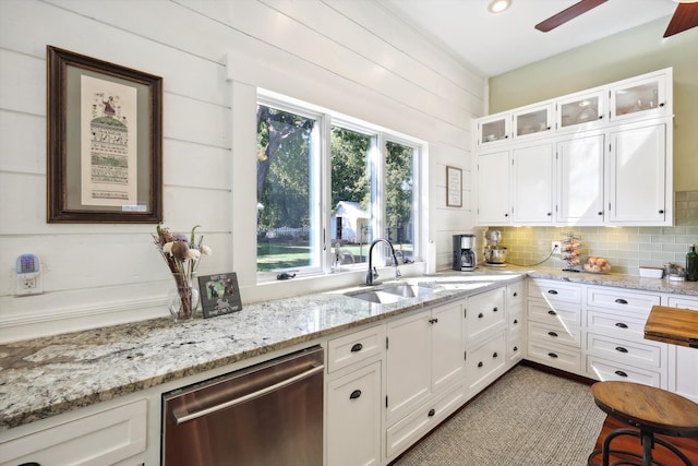 kitchen featuring white cabinetry, wood walls, light stone countertops, and stainless steel dishwasher