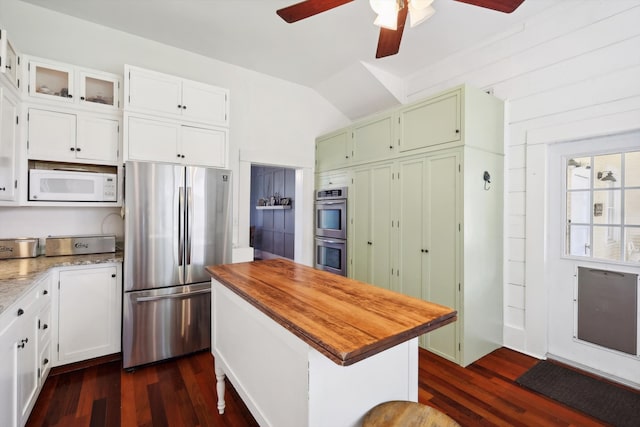 kitchen with appliances with stainless steel finishes, white cabinetry, ceiling fan, lofted ceiling, and dark hardwood / wood-style floors