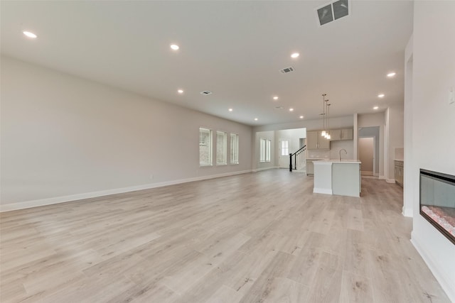 unfurnished living room with light hardwood / wood-style flooring and sink