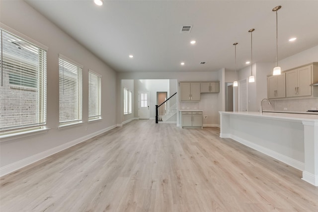 unfurnished living room with sink and light hardwood / wood-style floors