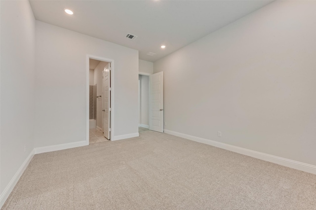 unfurnished bedroom with light colored carpet and connected bathroom