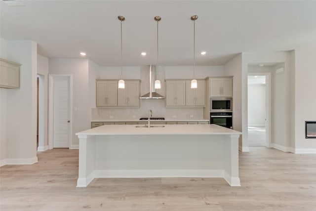 kitchen featuring wall chimney exhaust hood, stainless steel appliances, tasteful backsplash, pendant lighting, and light wood-type flooring