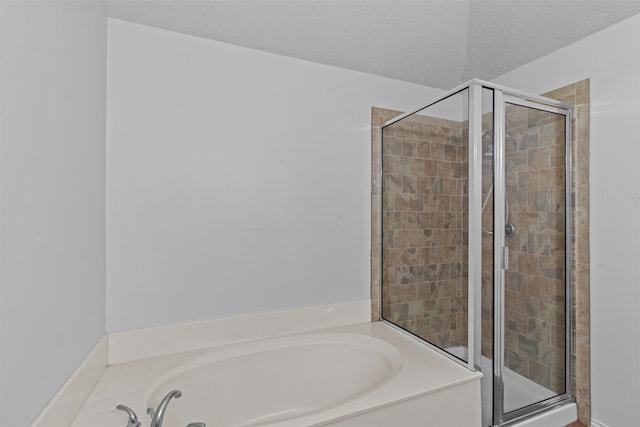 bathroom featuring a textured ceiling and shower with separate bathtub