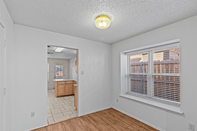 unfurnished room featuring a textured ceiling and light wood-type flooring