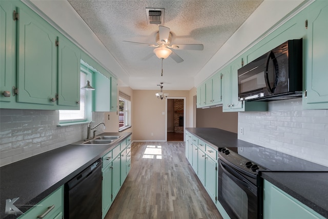 kitchen featuring tasteful backsplash, light hardwood / wood-style flooring, black appliances, ceiling fan with notable chandelier, and sink