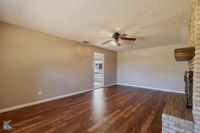 unfurnished living room with dark hardwood / wood-style floors, ceiling fan, a textured ceiling, and a brick fireplace