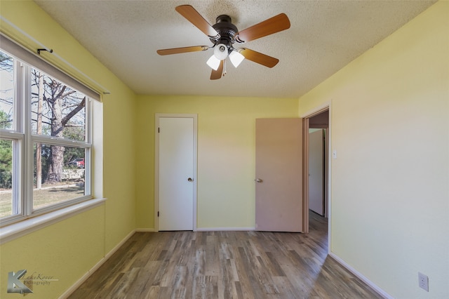 unfurnished bedroom with multiple windows, a textured ceiling, wood-type flooring, and ceiling fan